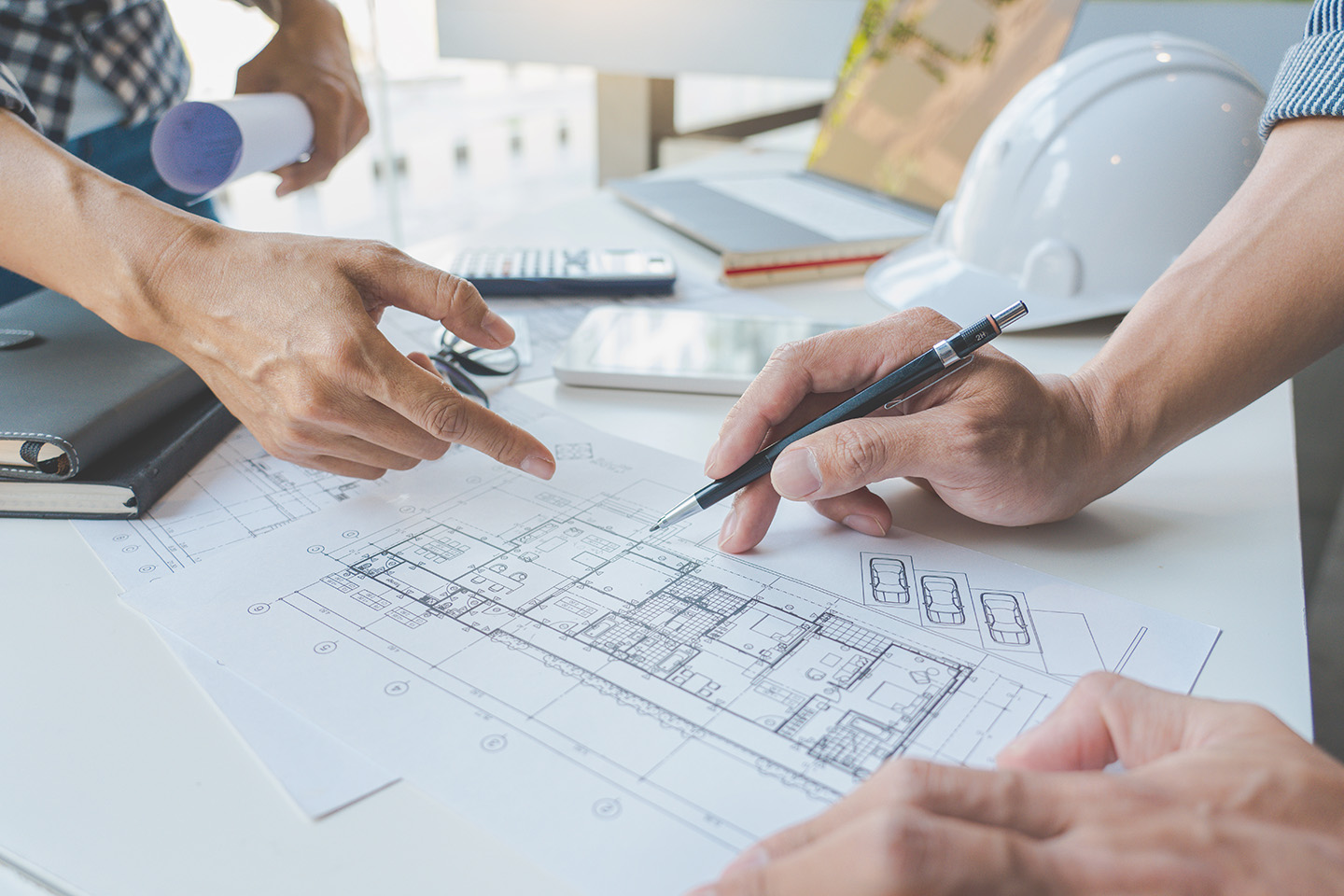 engineer Hand Drawing Plan On Blue Print with architect equipment discussing the floor plans over blueprint architectural plans at table in a modern office